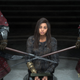 Frey sits bound on her knees in handcuffs with two guards armed with spears to either side of her.